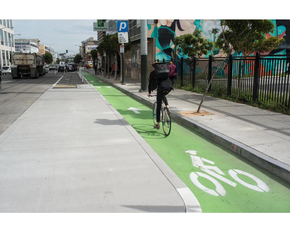 8th Street after: bicyclist riding in a bikeway protected by a loading island.