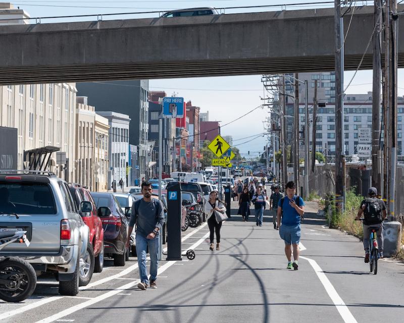 People walking under the freeway in the afternoon