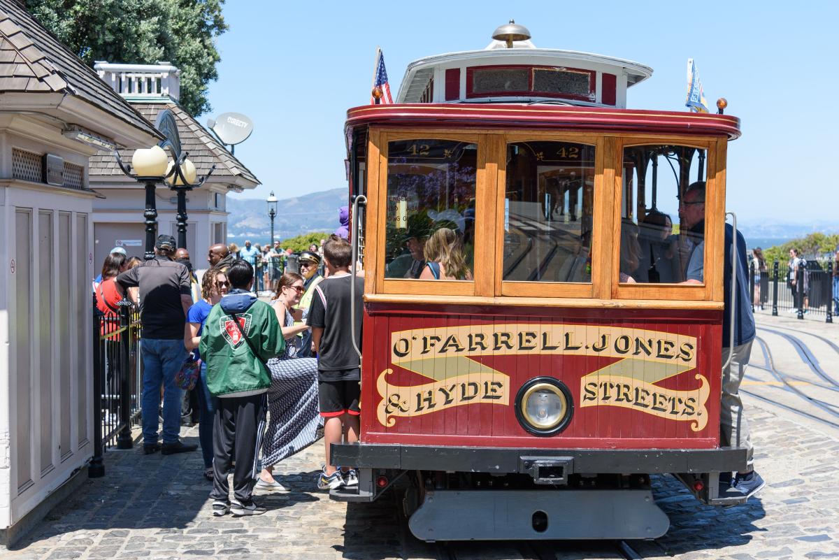 Cable car with sign that says "O'Farrell, Jones & Hyde Streets" picks up riders near Aquatic Park. Cable car with sign that says "O'Farrell, Jones & Hyde Streets" picks up riders near Aquatic Park.