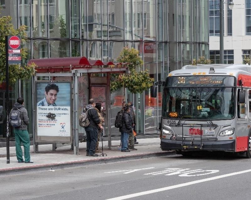 Photo of passengers at a bus shelter as a bus is arriving